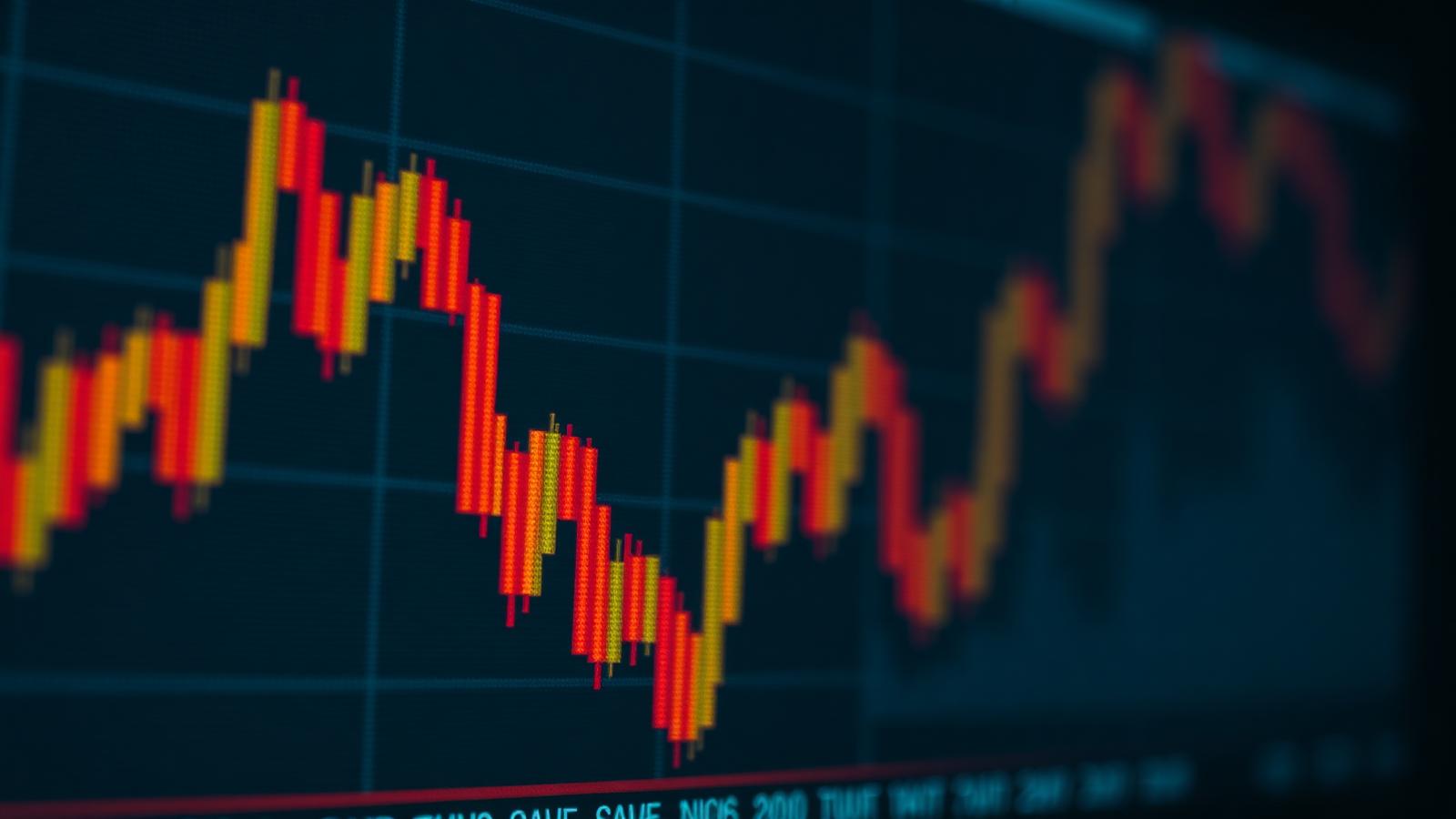 Blurred amber candlestick charts on a trading terminal in a darkened room